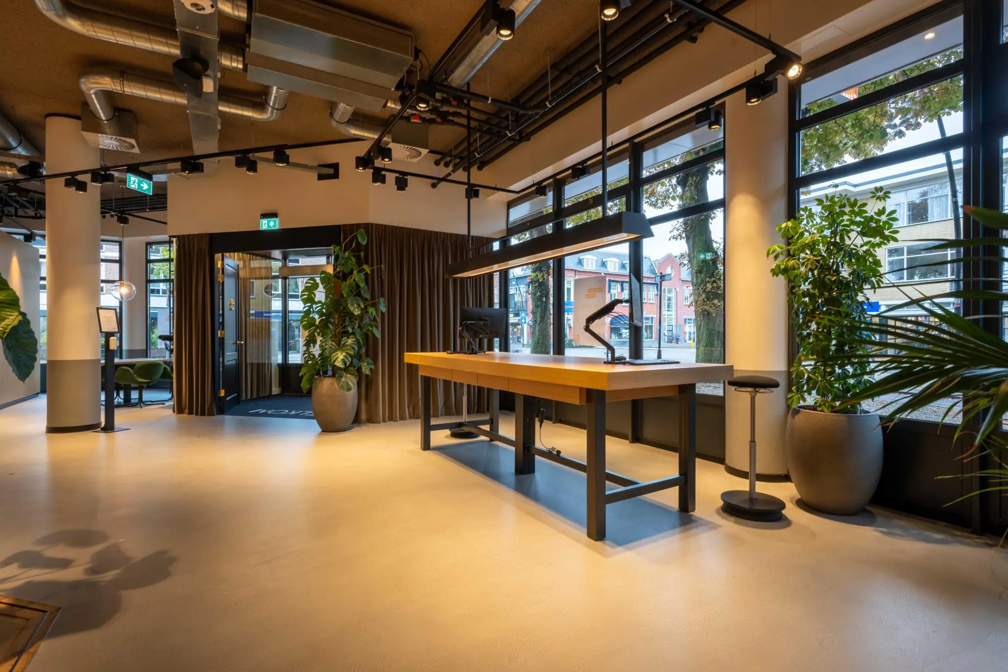 Moderne, lichte ontvangsthal aan de 1e Hogeweg met een grote houten balie, industriële details en veel ramen met uitzicht op de straat.